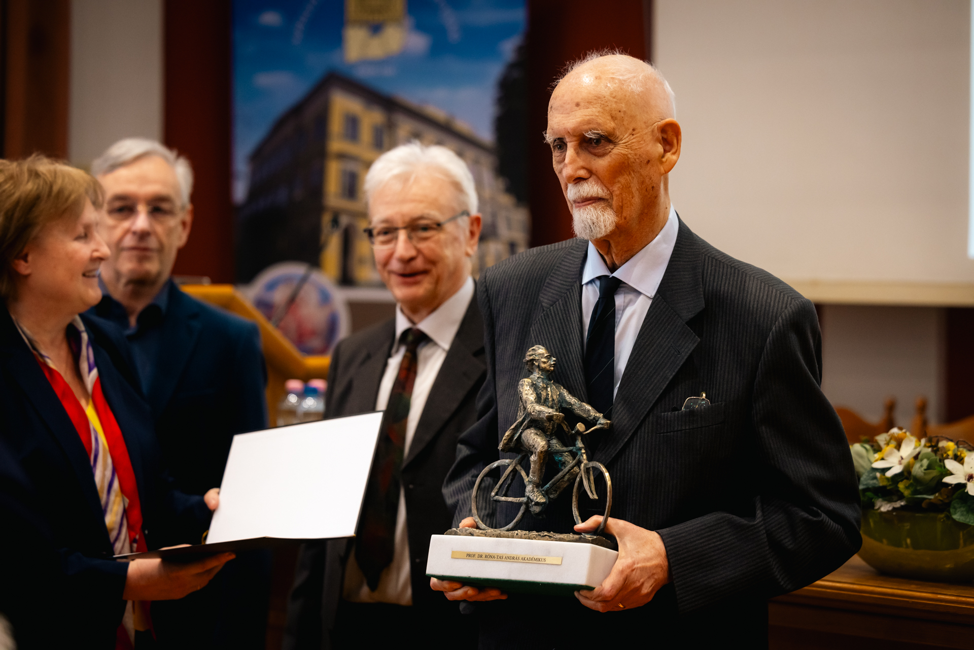 Dr. Róna-Tas András átveszi a díjat Dr. Hohmann Judittól és Dr. Kemény Lajostól, mellettük a SZAB elnöke, Dr. Krisztin Tibor látható.